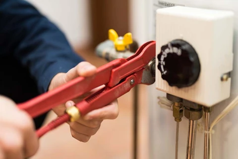 Intérieur d'un local technique avec plombier effectuant maintenance sur installation de chauffage